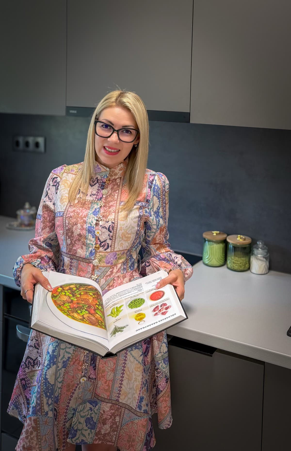 Petrus Emese a konyhájában, kezében egy nyitott szakácskönyvvel